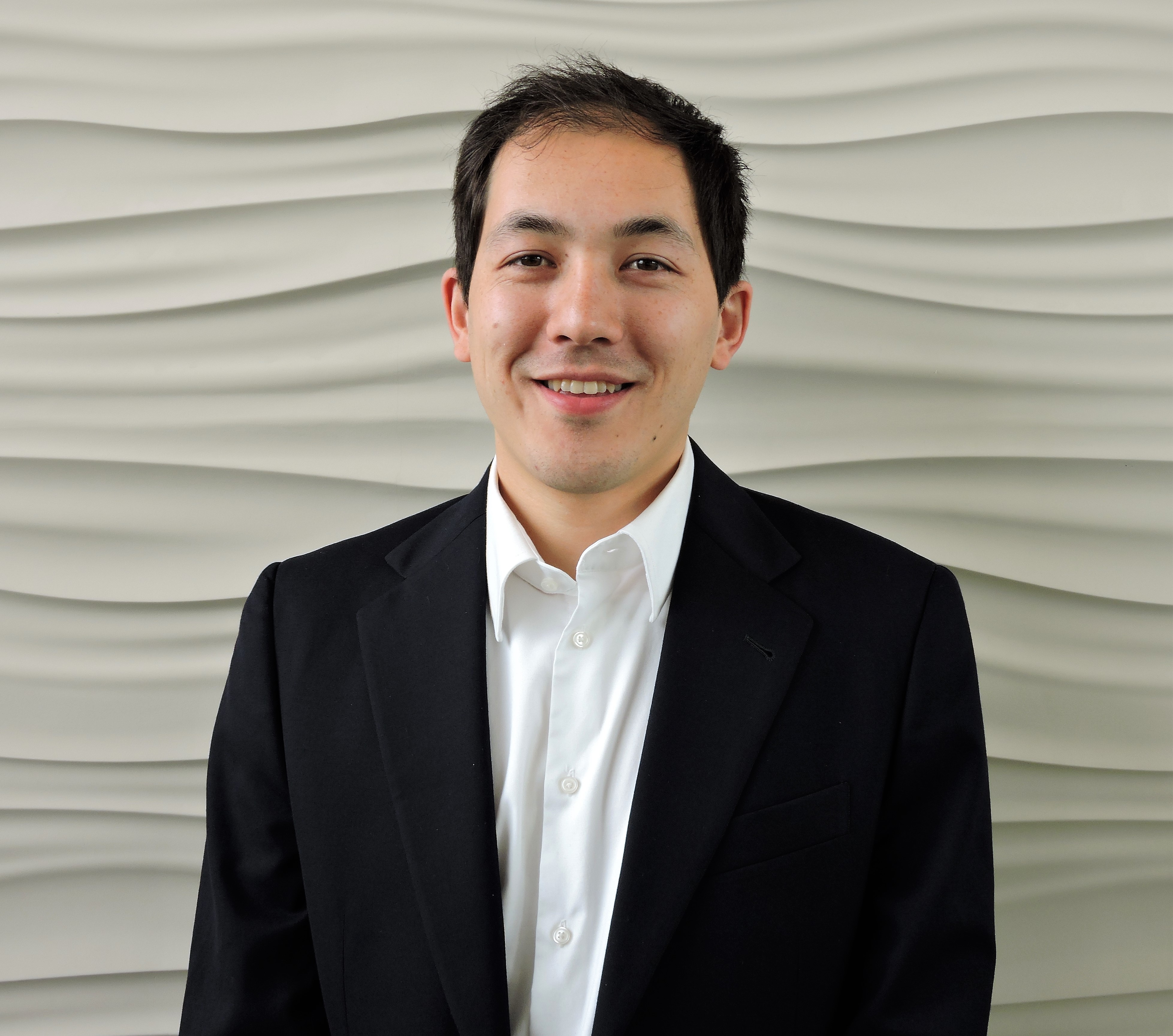 Photo of Matt Fowle in a suit in front of a white textured backdrop.